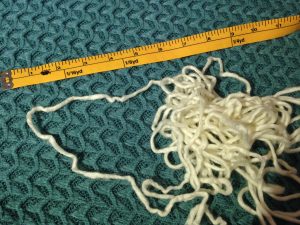 Cream colored mystery yarn next to a measuring tape
