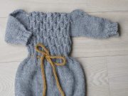 Grey knitted romper for baby or toddler girl, with long sleeves, drawstring at waist and buttons between leg openings for easy diaper change