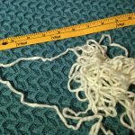 Cream colored mystery yarn next to a measuring tape